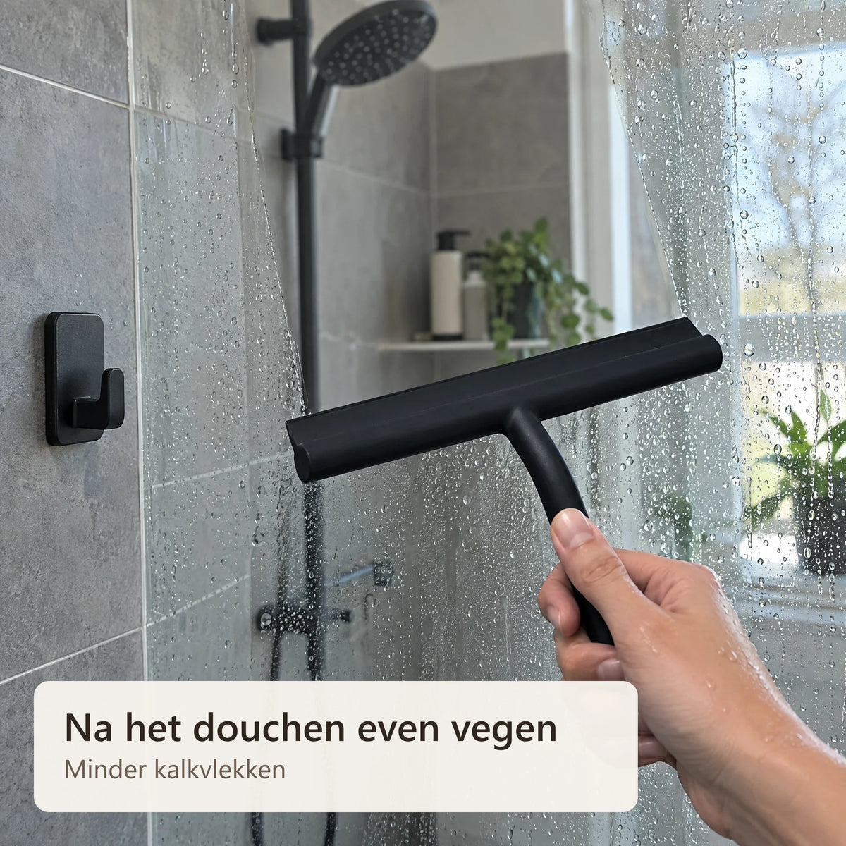 De glazen douchewand wordt drooggeveegd met de wisser