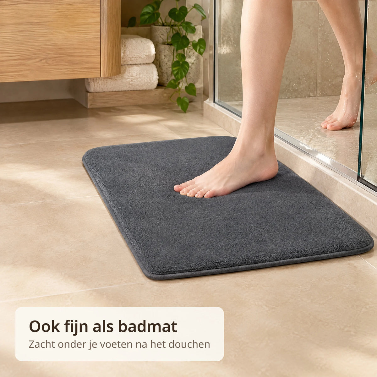 Blote voet stapt uit de douche op de grijze absorberende mat in de badkamer
