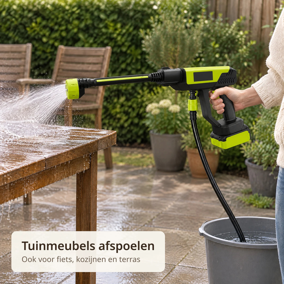 Draadloze hogedrukspuit spoelt een houten tuintafel af op het terras, met een emmer water ernaast