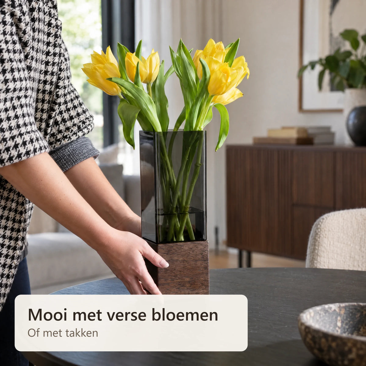 De vaas met gele tulpen wordt op tafel gezet