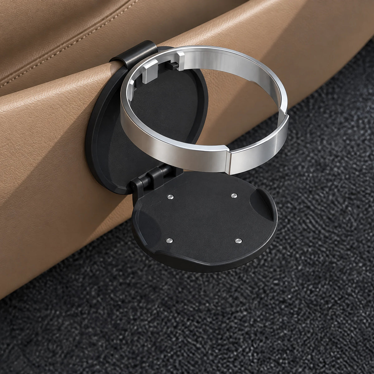 Zwarte opvouwbare bekerhouder voor de auto, uitgeklapt en vastgeklemd op de rand van een beige portiervak