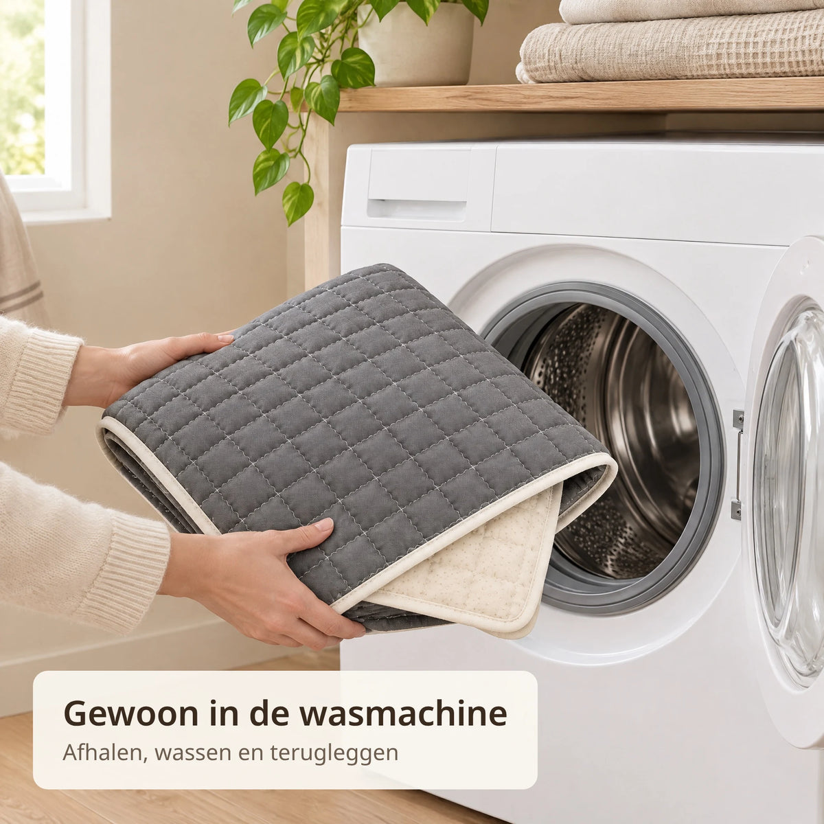 Twee handen stoppen de opgevouwen donkergrijze bankbeschermer in de wasmachine