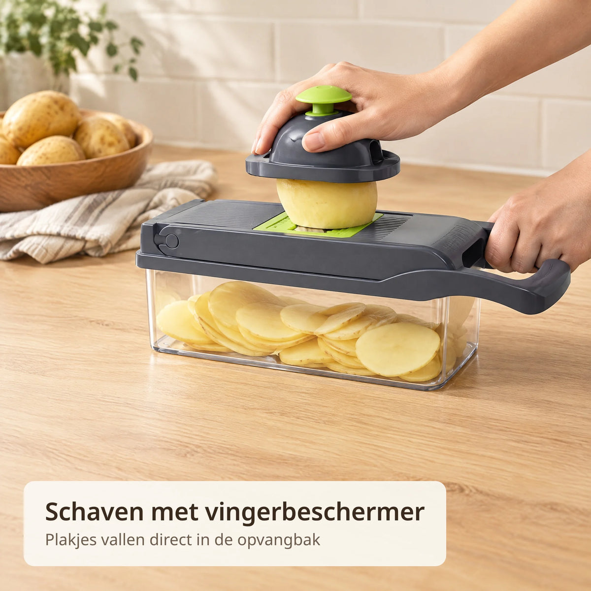 Hand schaaft een aardappel met de vingerbeschermer over de groentesnijder, de plakjes liggen in de opvangbak