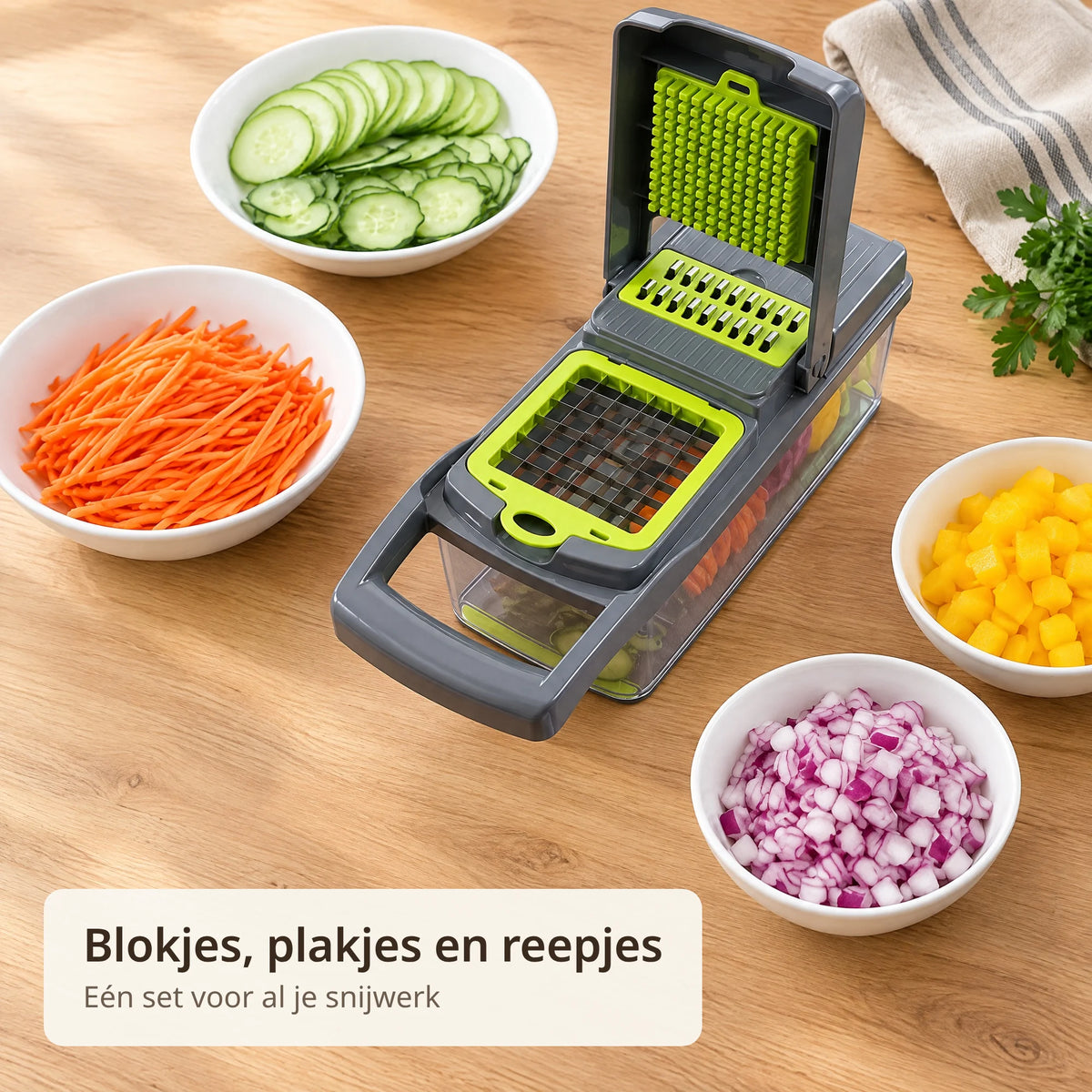 Groentesnijder op het aanrecht tussen schaaltjes met komkommerplakjes, wortelreepjes en blokjes ui en paprika