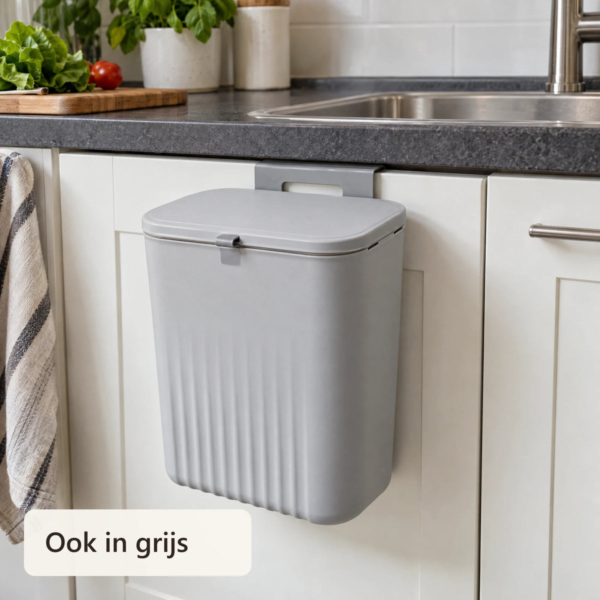 Grijze afvalbak aan een witte keukenkastdeur
