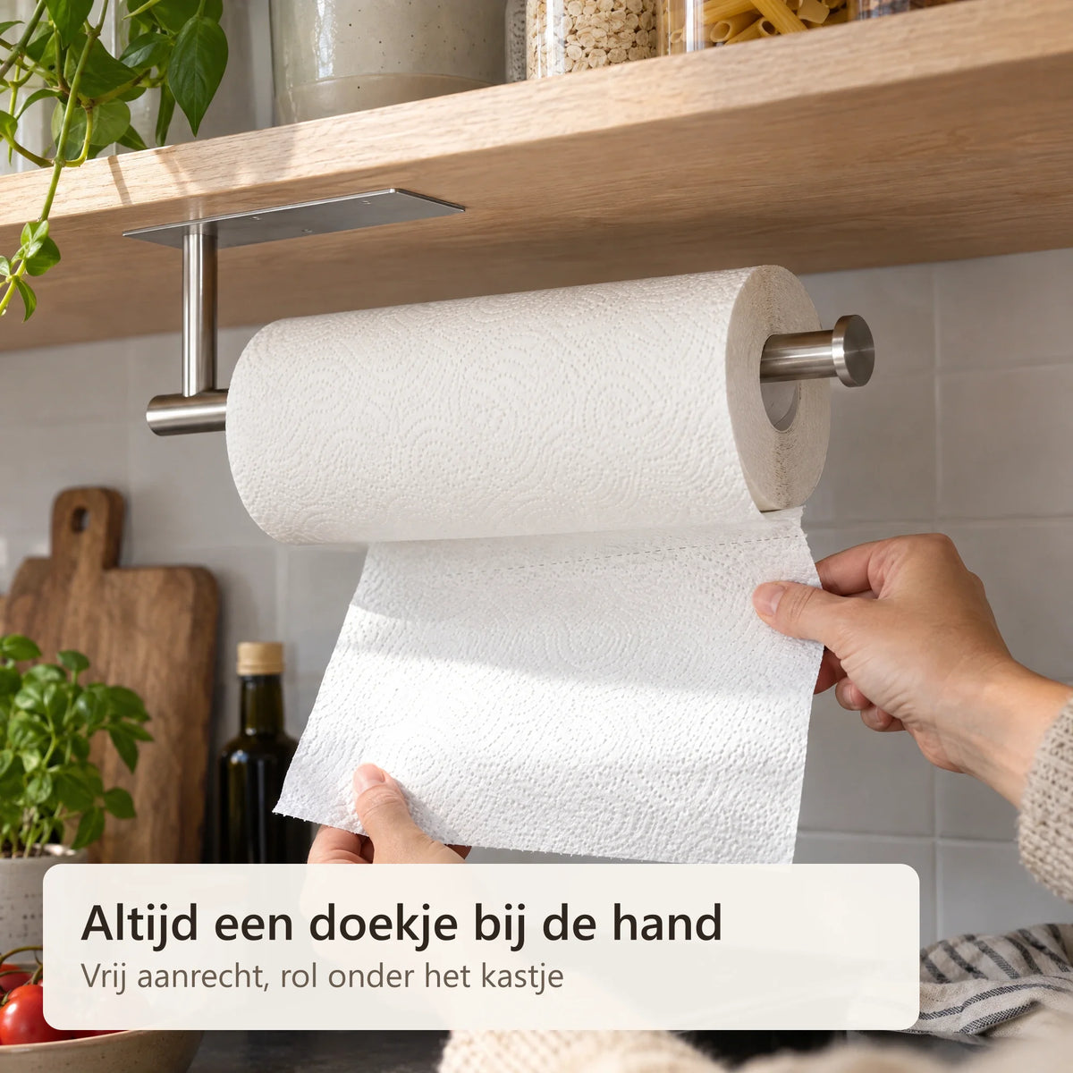 Een hand scheurt keukenpapier af van de rol onder het kastje
