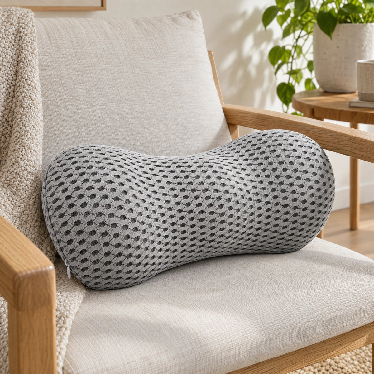 Grijs memory foam lendenkussen met mesh hoes op een lichte fauteuil