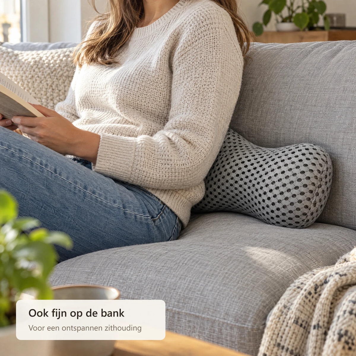 Iemand leest op de bank met het lendenkussen achter de onderrug