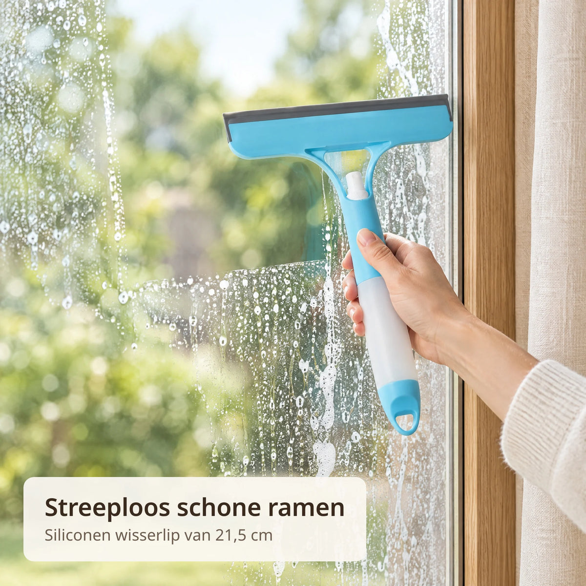 Hand trekt met de blauwe raamwisser een schone baan over een nat raam met sop