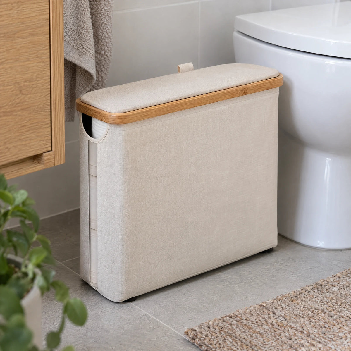 Beige opbergbox voor toiletrollen met bamboe rand naast het toilet