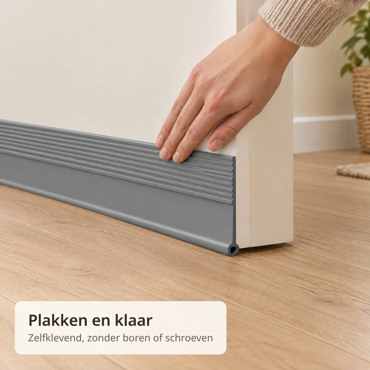 Hand drukt de grijze zelfklevende tochtstrip vast op de onderkant van een deur